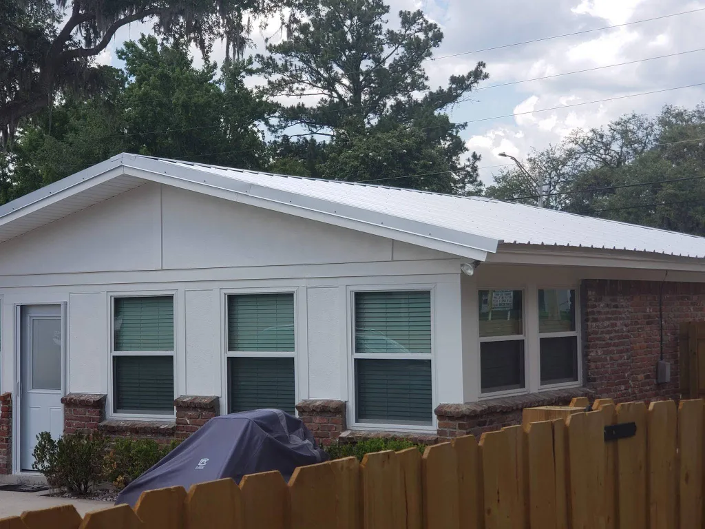 Residential single story home with newly white metal roof in the process of being installed.